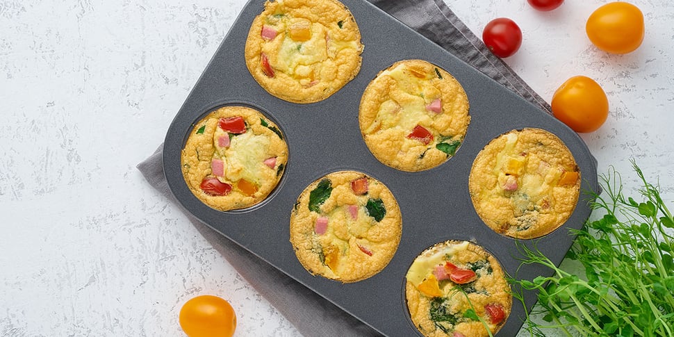 Baked Egg Bites on a muffin pan on top of a white background