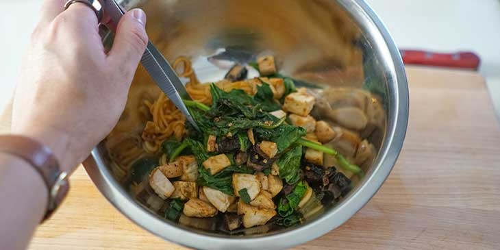 All chicken and mushroom sauced-noodle ingredients being mixed on a stainless steel bowl