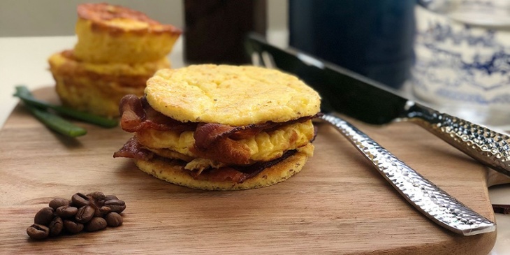 keto breakfast sandwich placed next to utensils and coffee beans on a wooden board